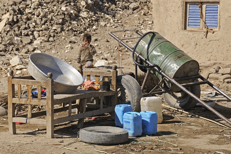 Boy in the dirt in front of house